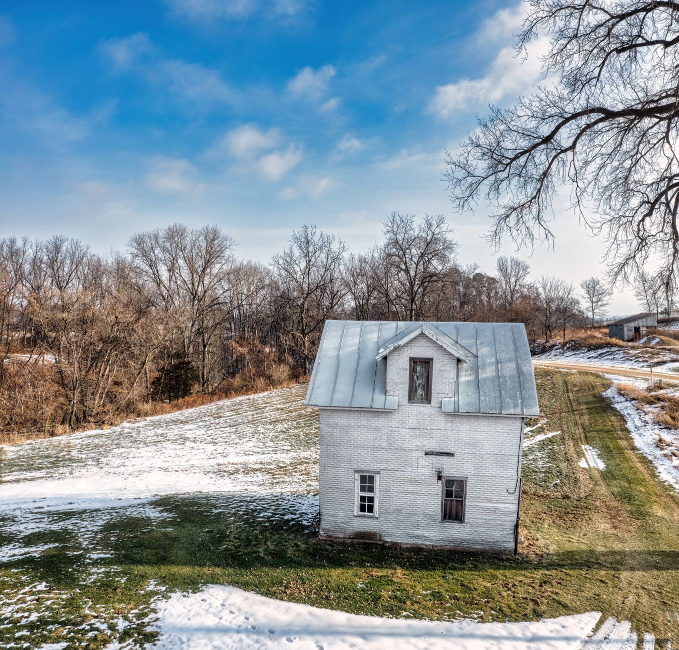 Aerial view of an old white house in rural Kellogg, MN with