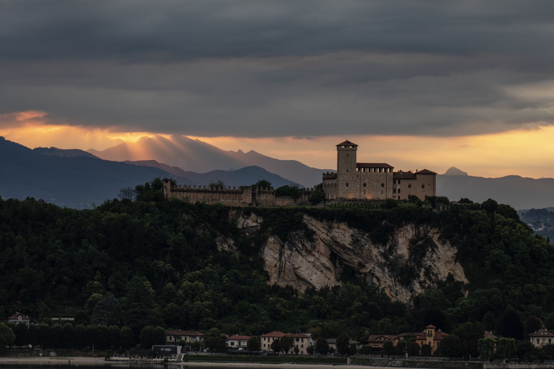 Majestic castle on a hill with sunset backdrop, rugged cliff, and town