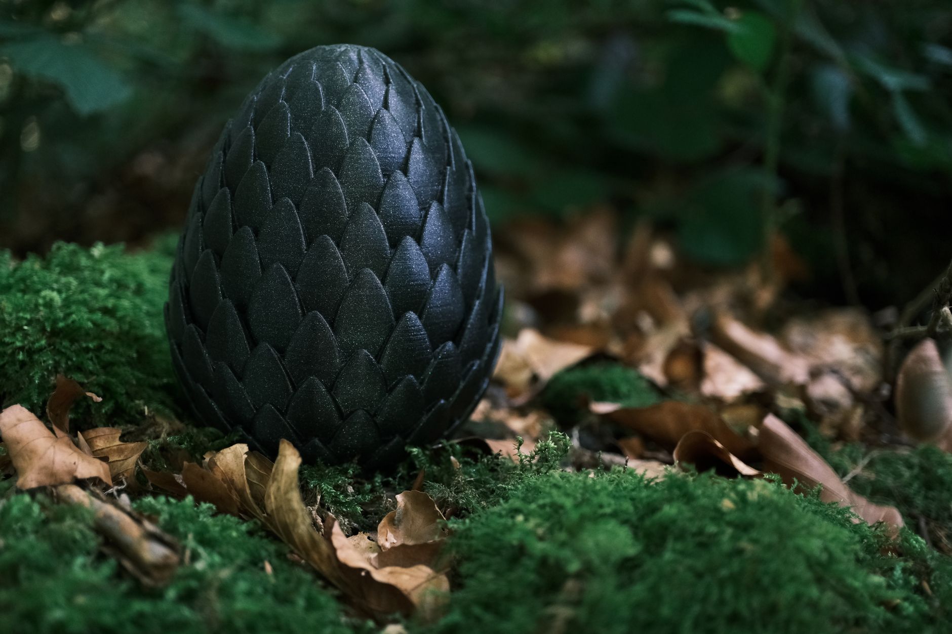 Intriguing black dragon egg-like sculpture set in a lush forest environment, surrounded