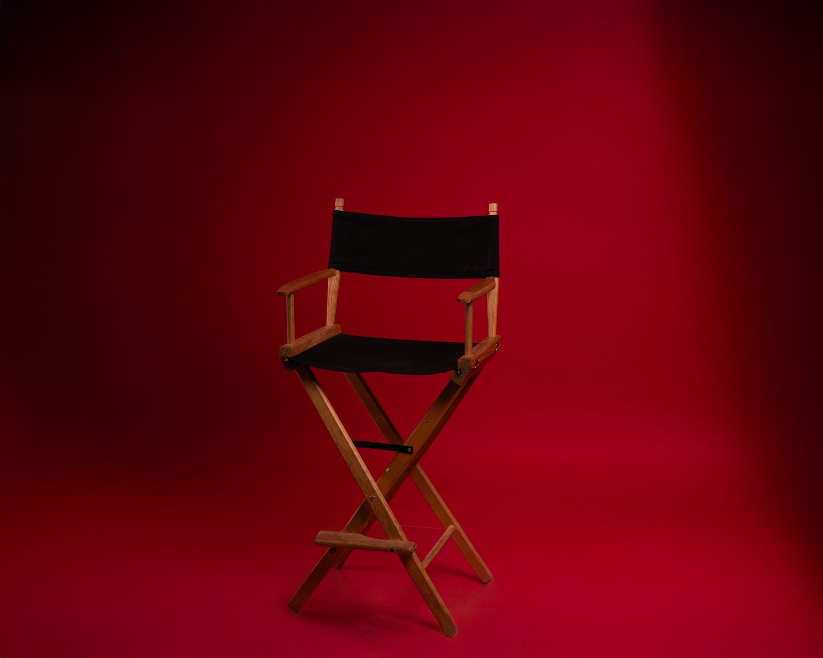 A wooden director's chair against a vibrant red backdrop, symbolizing film industry