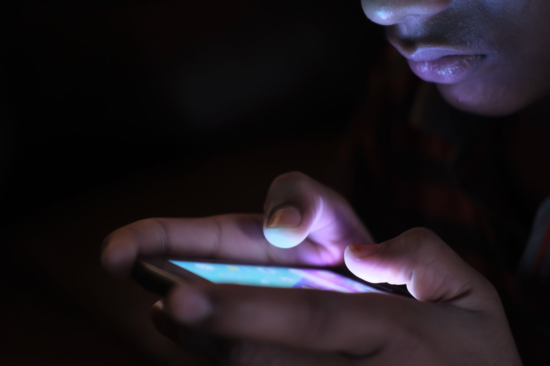 Close-up of a person holding and using an illuminated smartphone in a