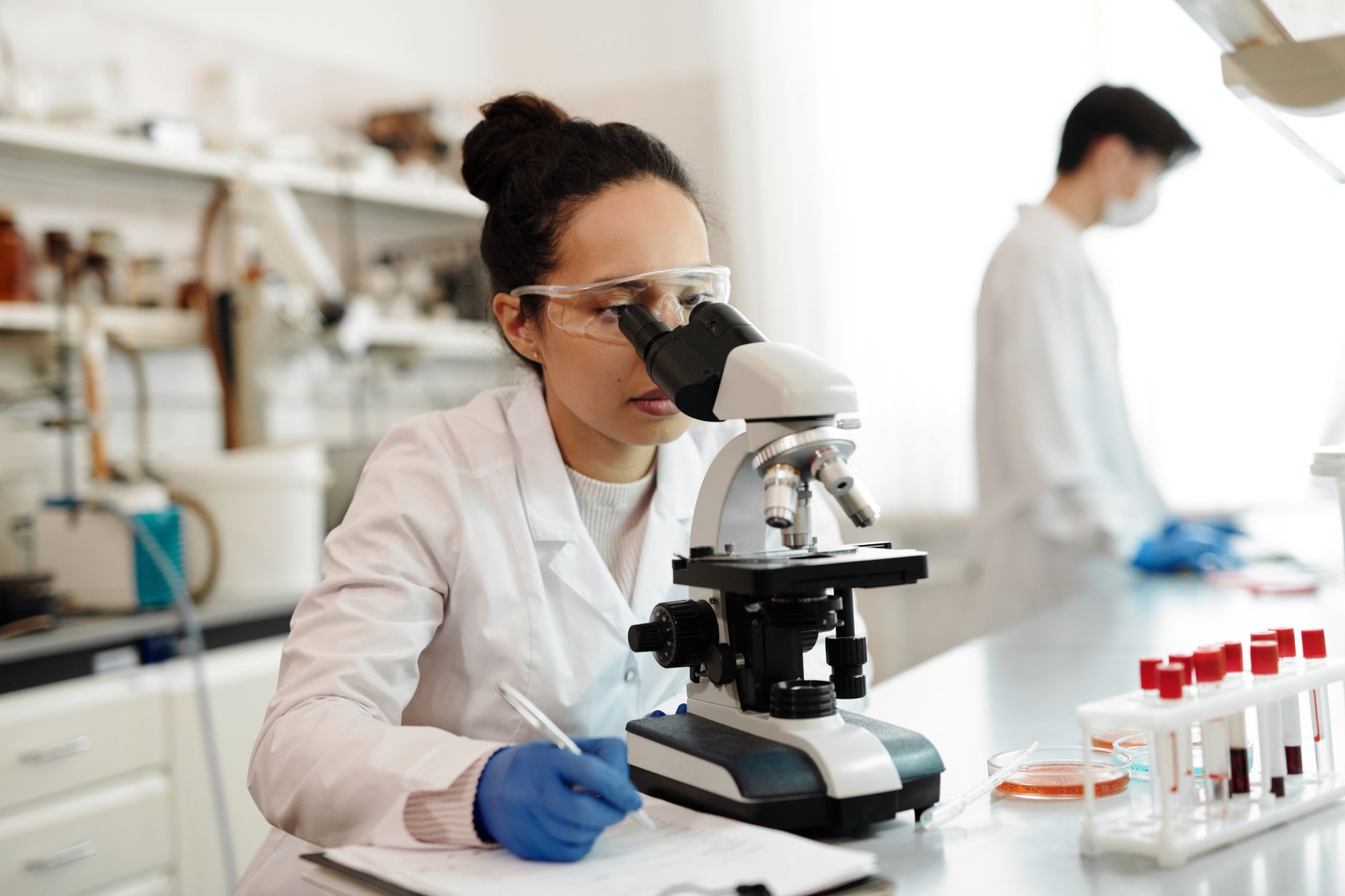 A scientist in a lab coat using a microscope in a modern