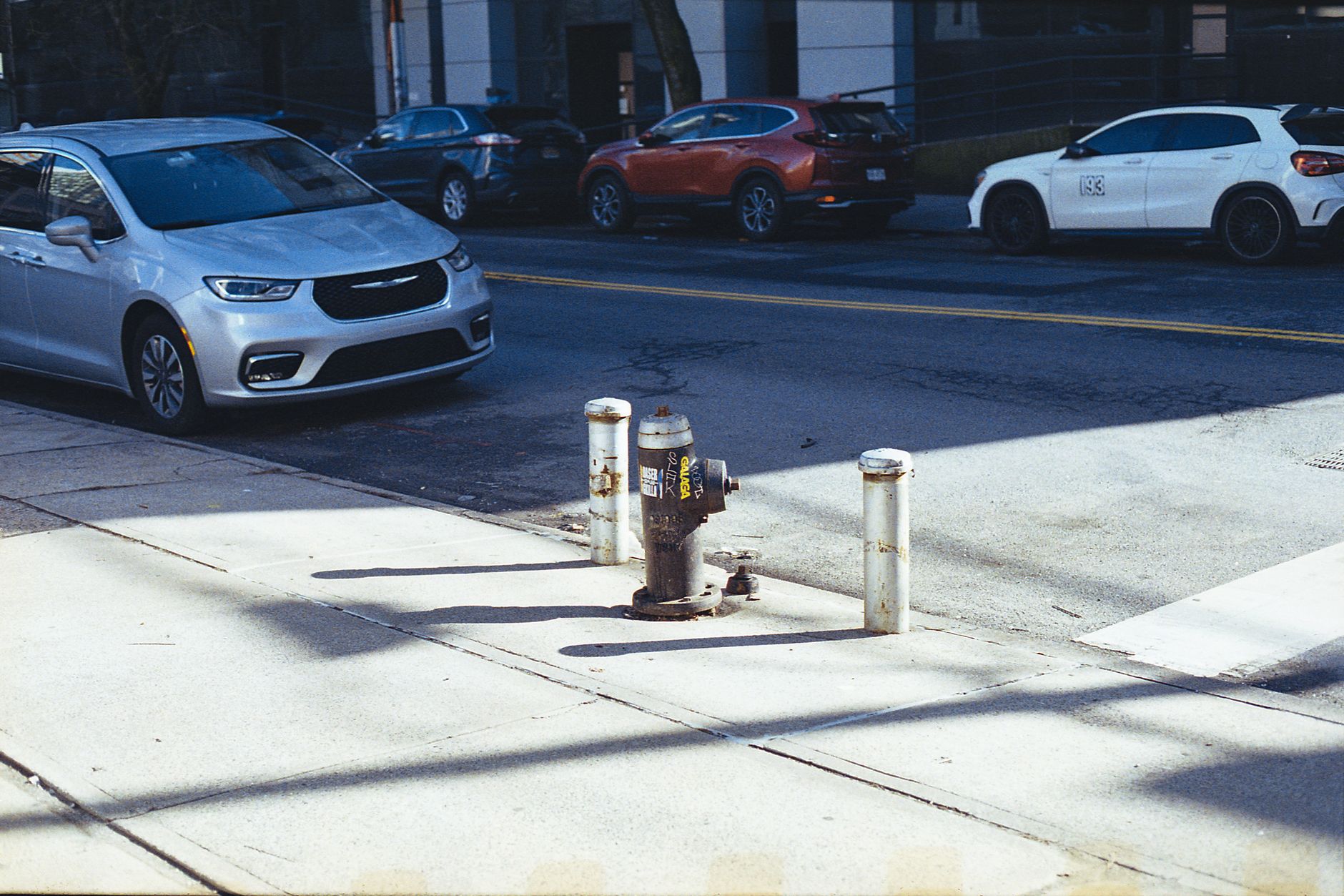 A typical New York City street featuring a fire hydrant, sidewalk, and parked cars in an urban setting.