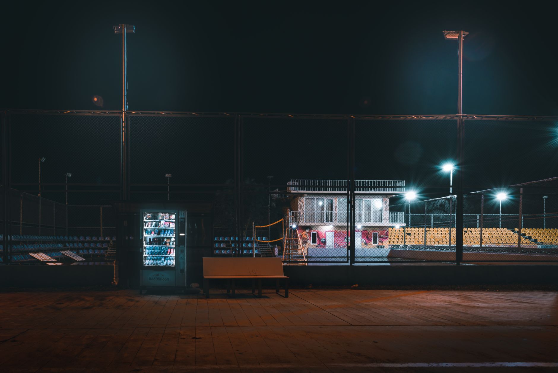 Atmospheric view of a sports complex at night featuring a bench and
