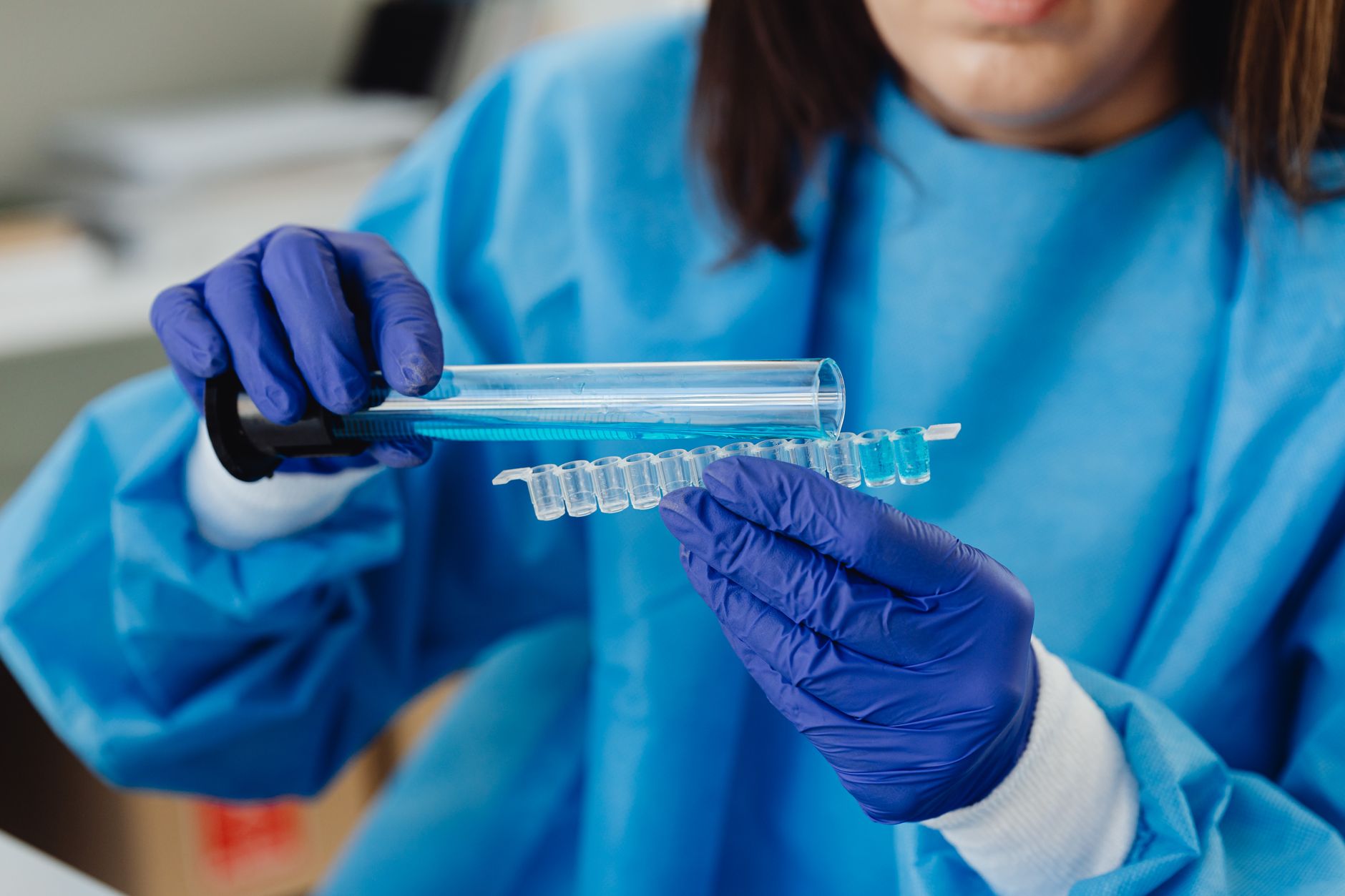 Scientist in blue protective gear conducting laboratory analysis with test tubes and