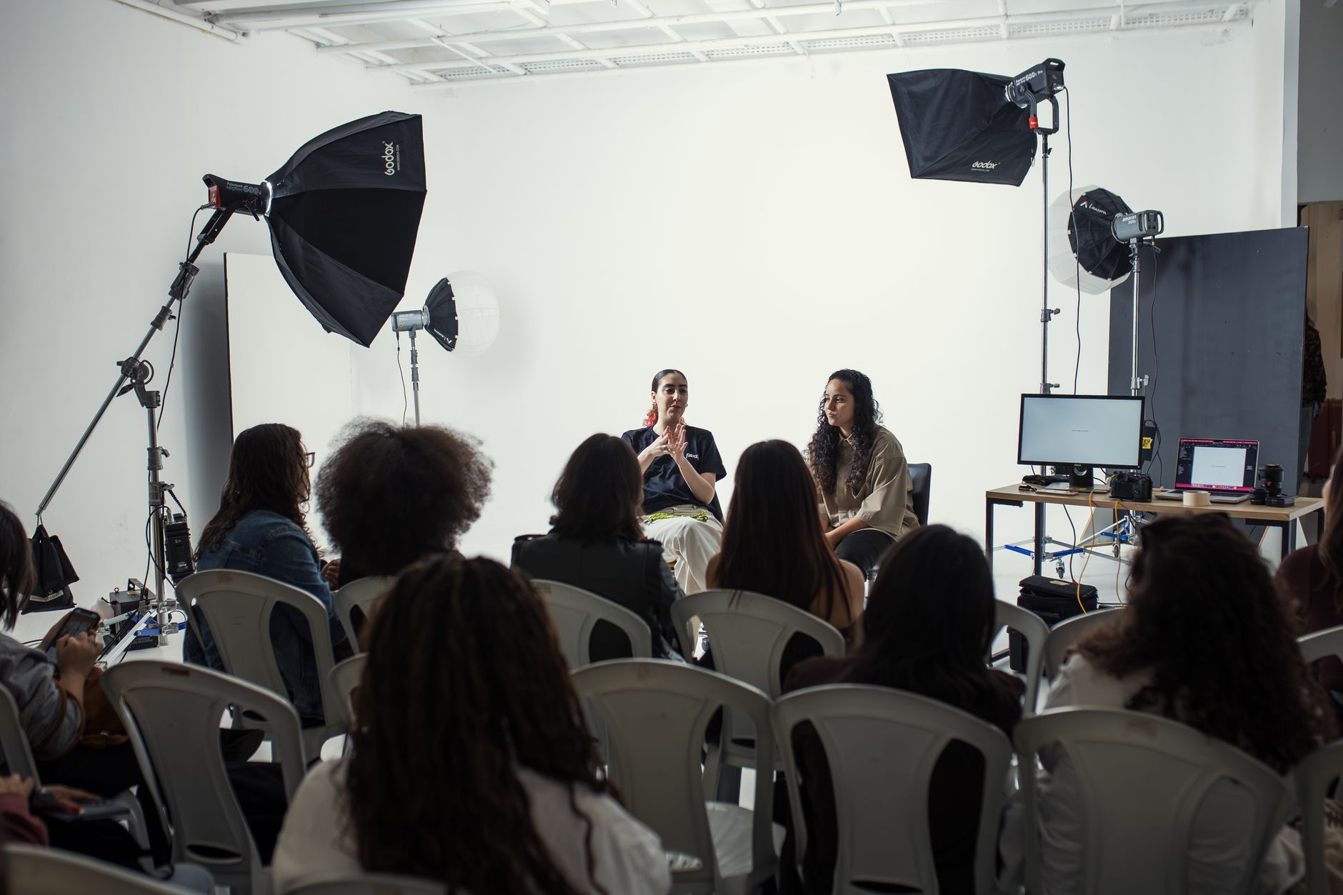 Audience attending a professional photography workshop indoors with studio lighting setup.