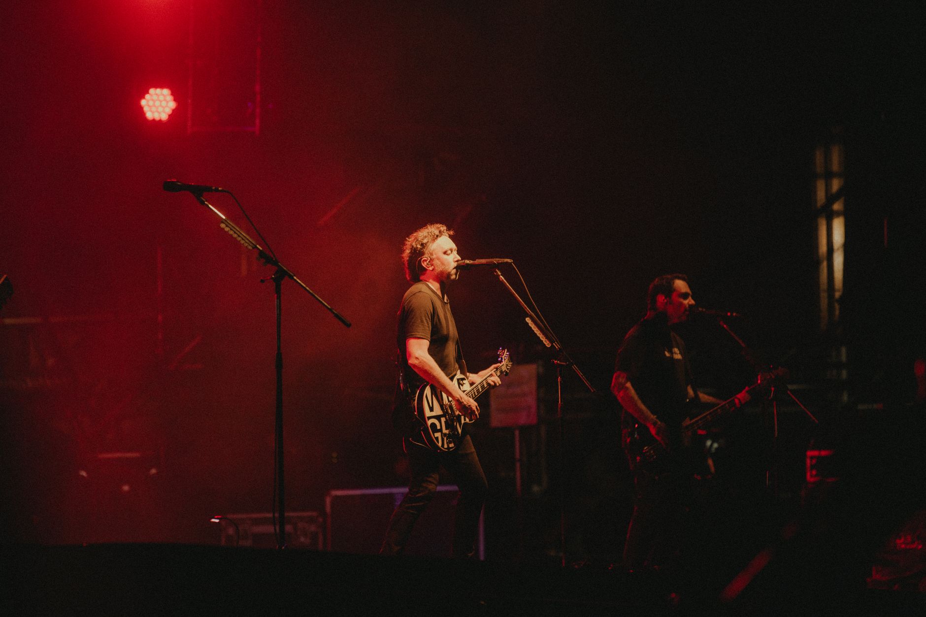 Live rock band performing on stage with vibrant red lighting creating a