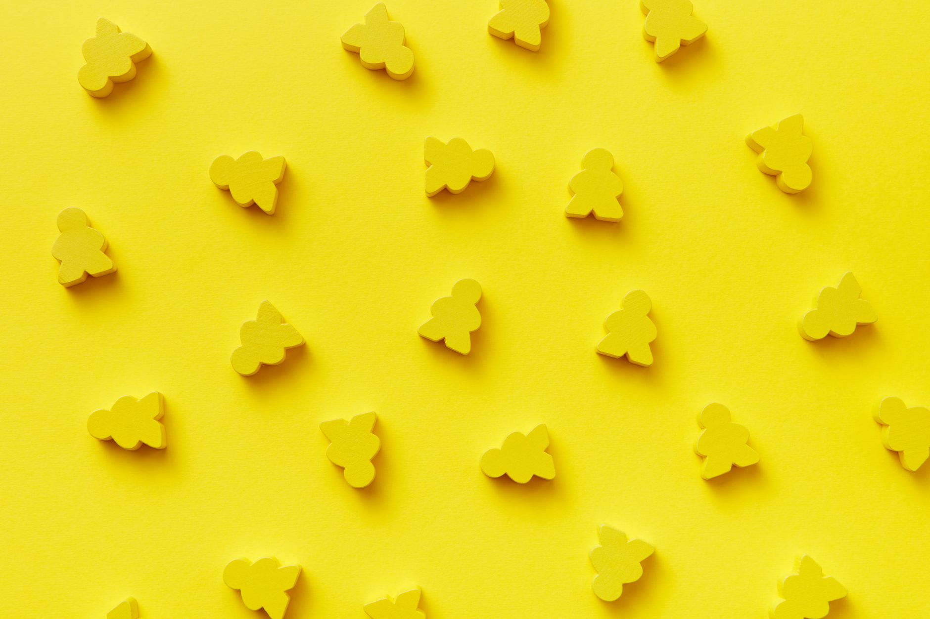 Bright yellow abstract pattern with toy meeples against a yellow background, ideal