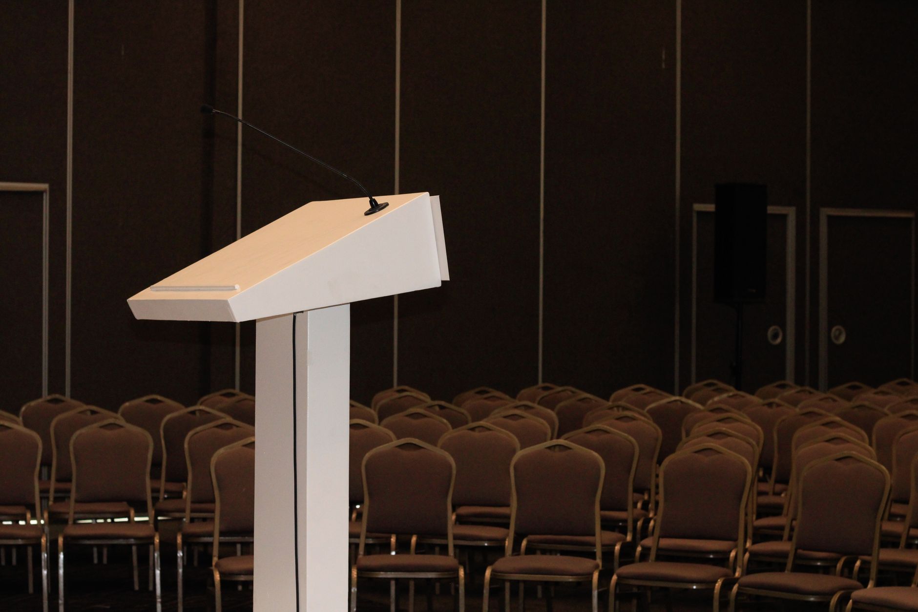An empty conference room setup with podium and rows of chairs, ready