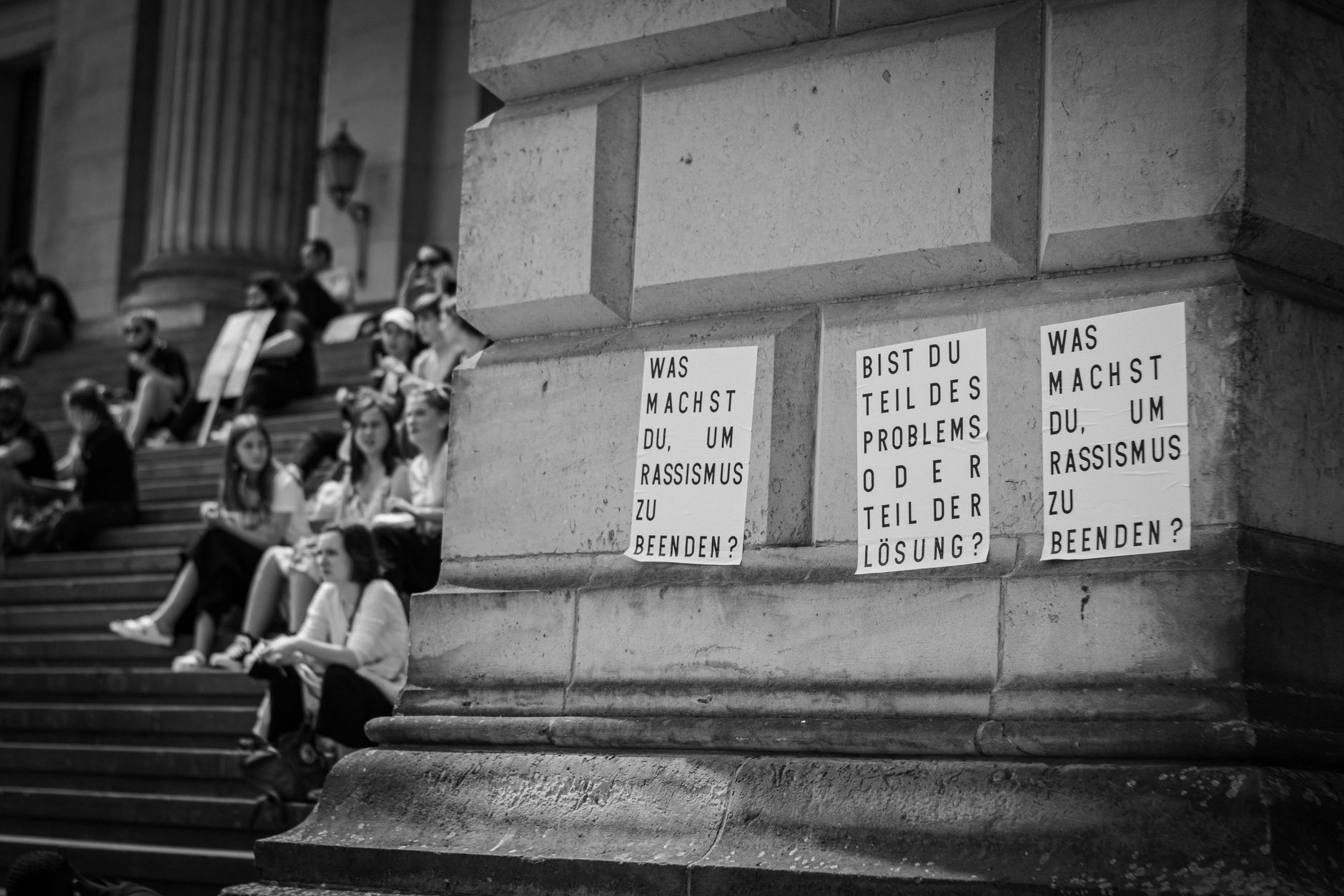 Protesters gather in Berlin, Germany, with anti-racism messages displayed, captured in black