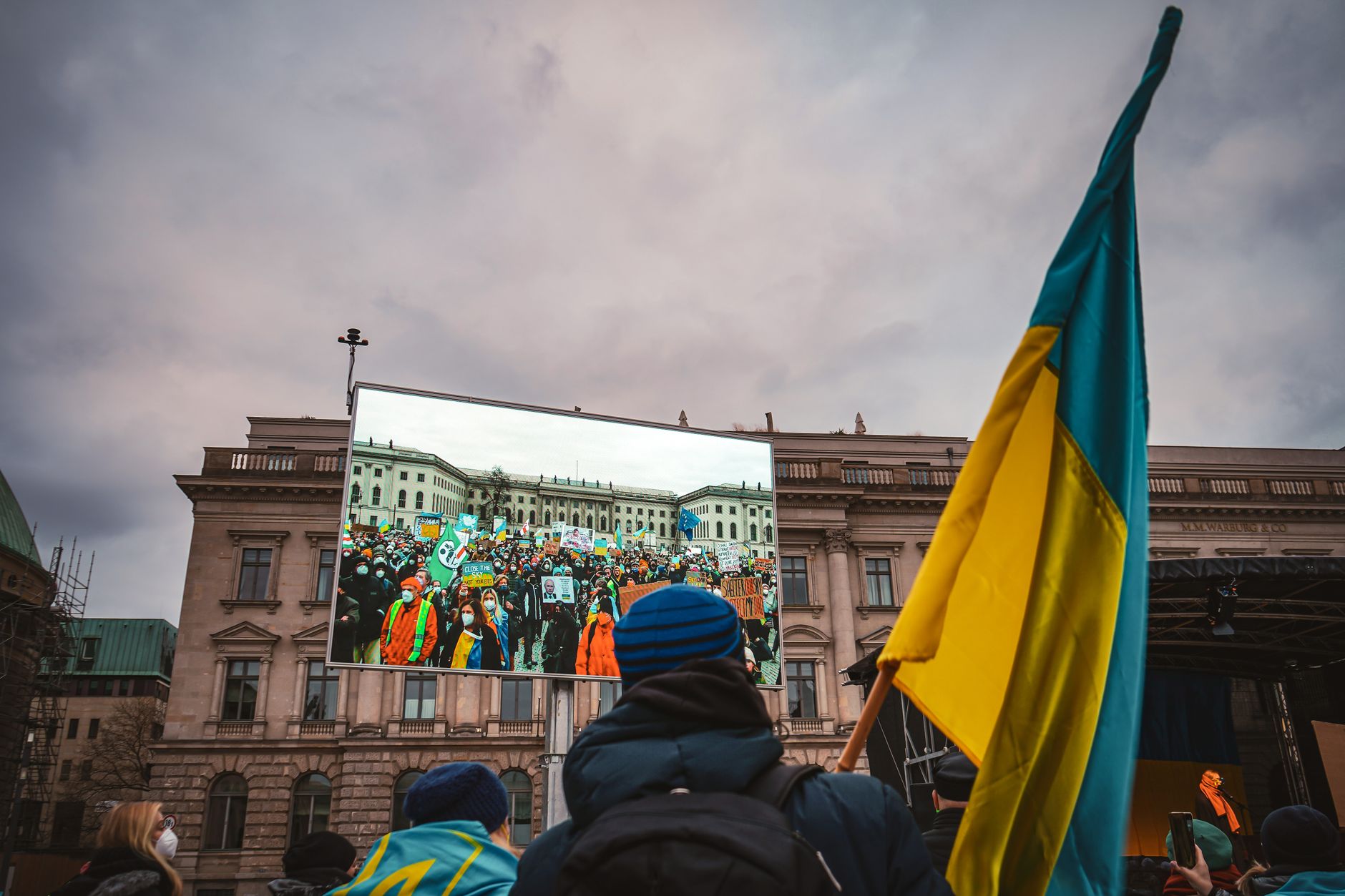 Crowd gathers in Berlin for a protest rally, with Ukrainian flag prominently