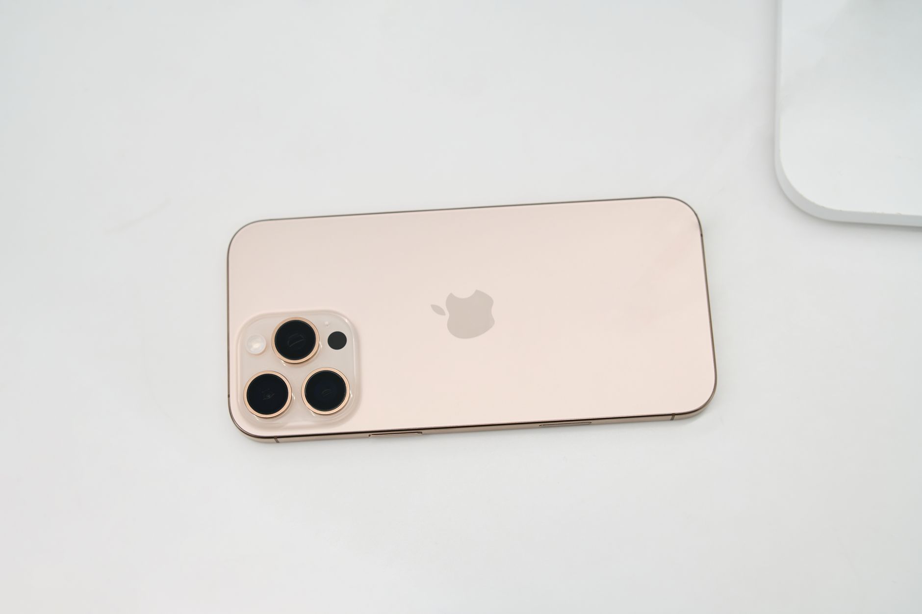Gold smartphone featuring a triple-lens camera setup placed on a clean white