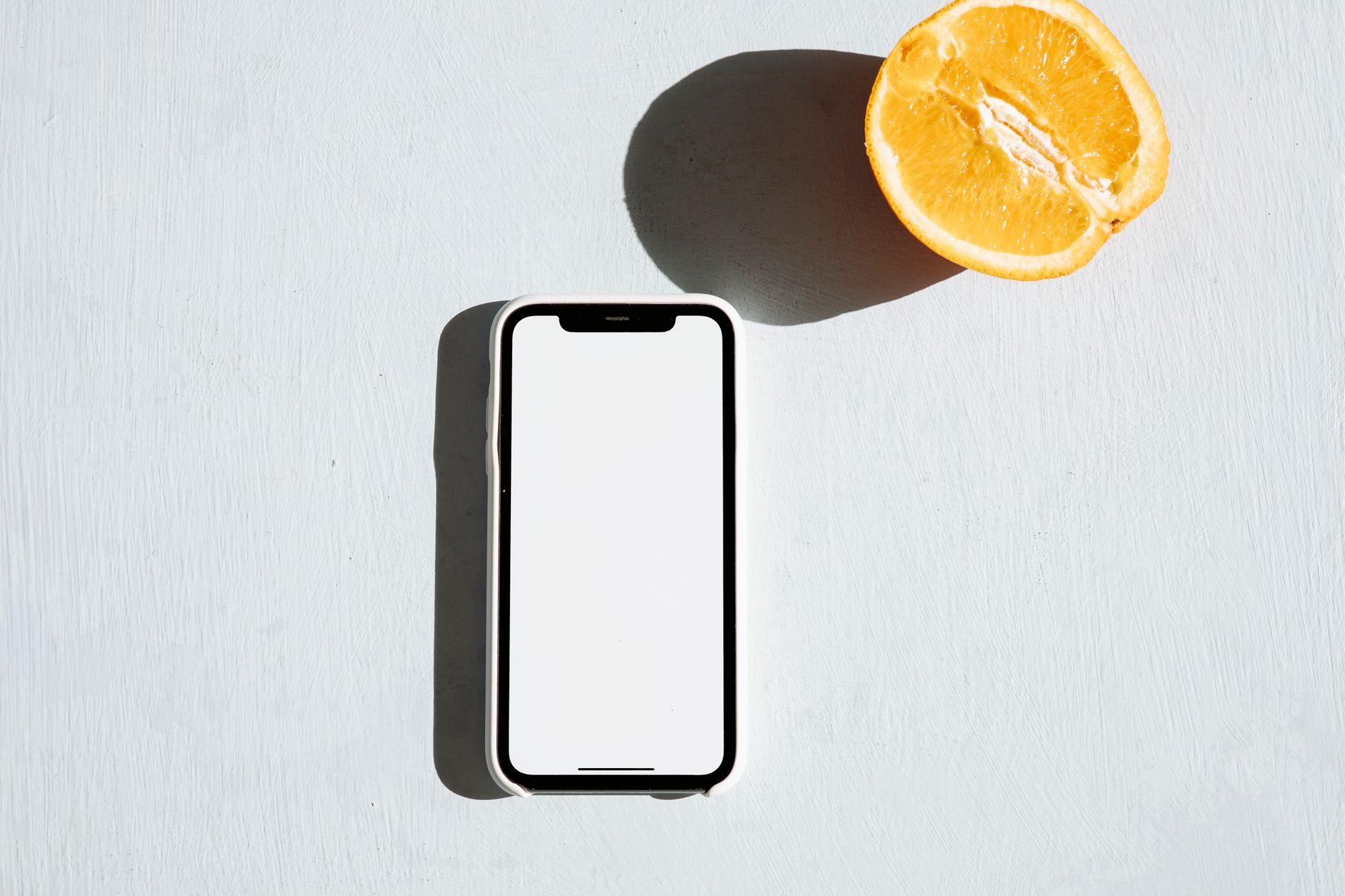 A smartphone with a blank screen next to an orange slice on