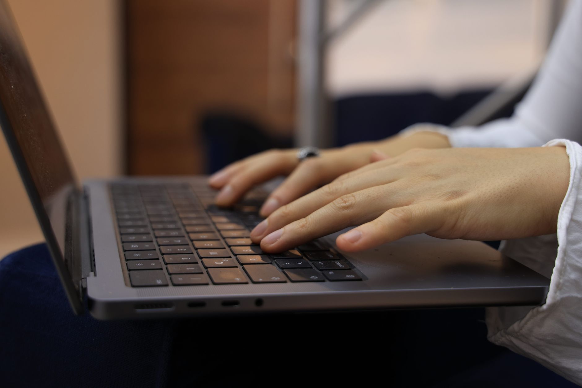 Hands typing on a laptop keyboard in an indoor setting. Perfect for