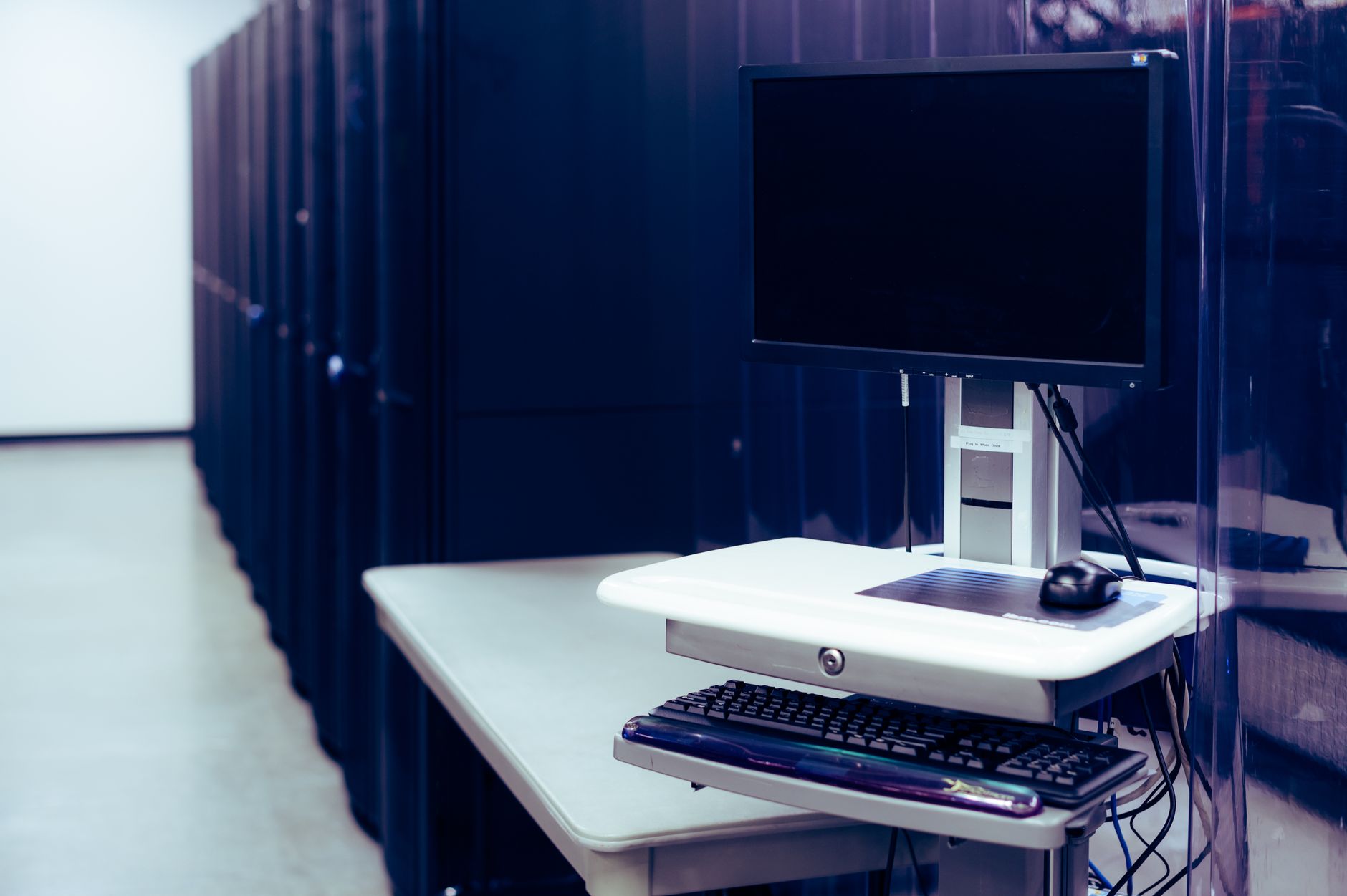 Contemporary computer with black screen placed on stand near row of server