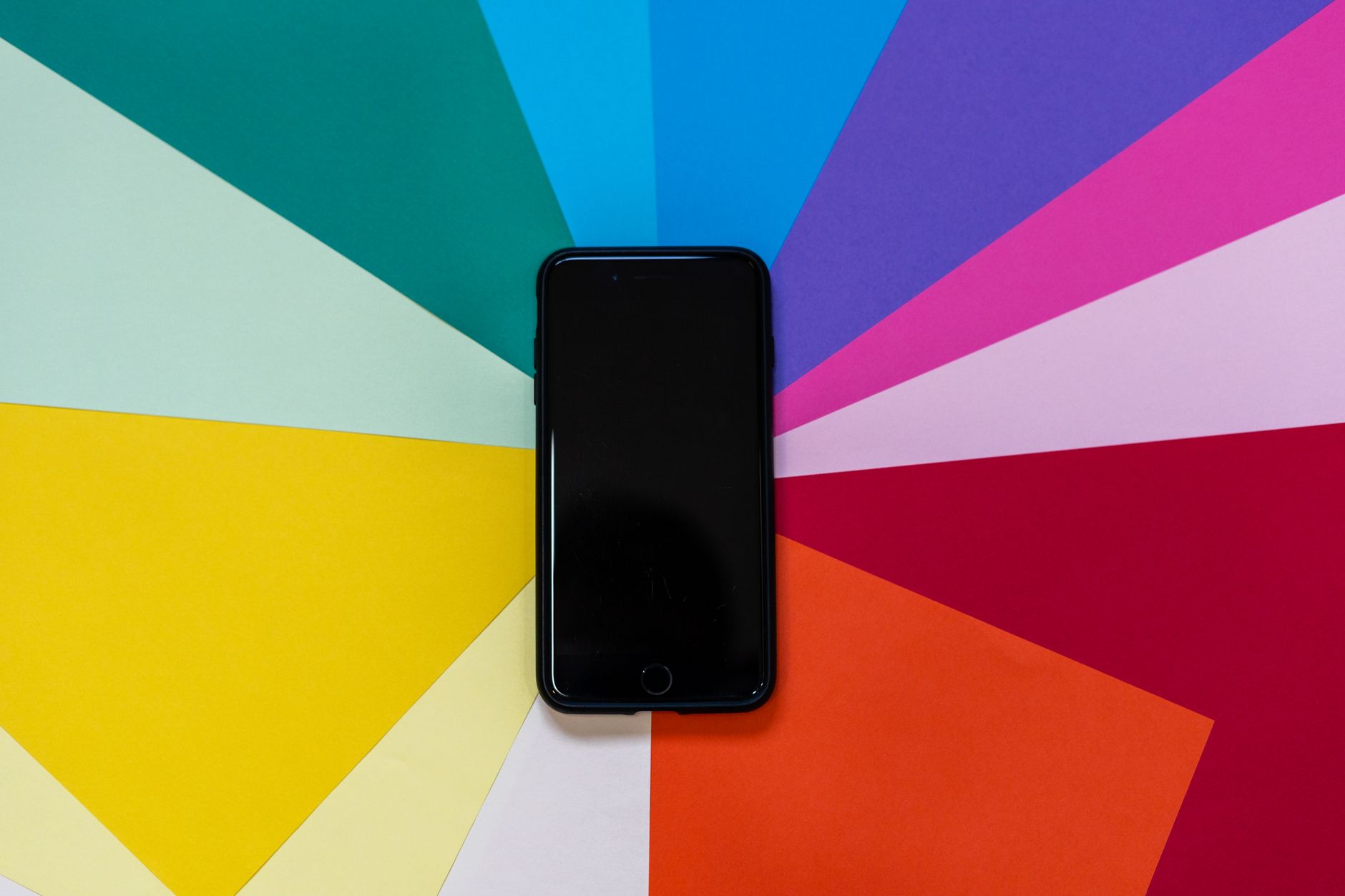 A smartphone placed on a colorful paper background, showcasing vibrant hues in
