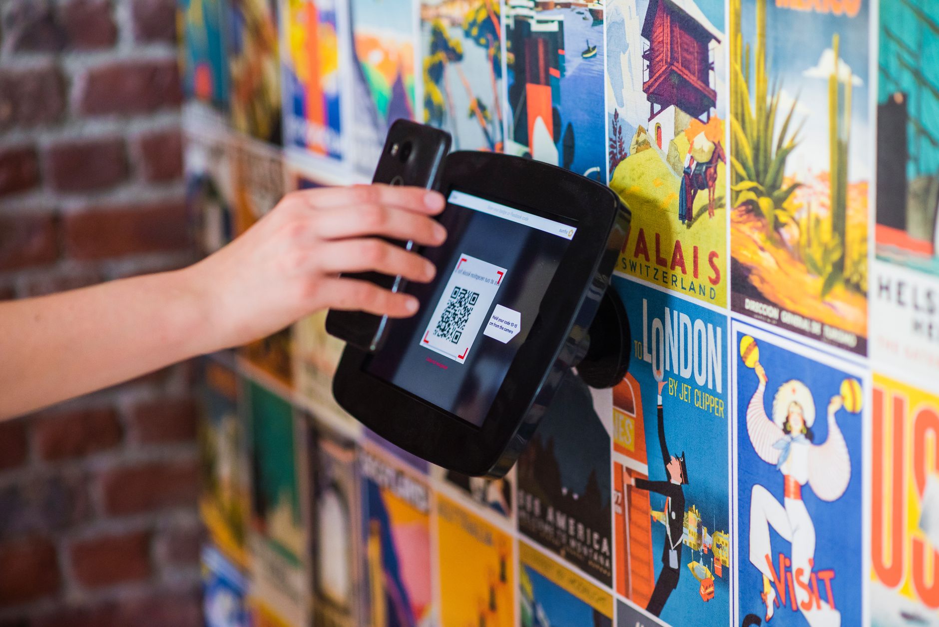 A hand scanning a QR code with a smartphone on a wall