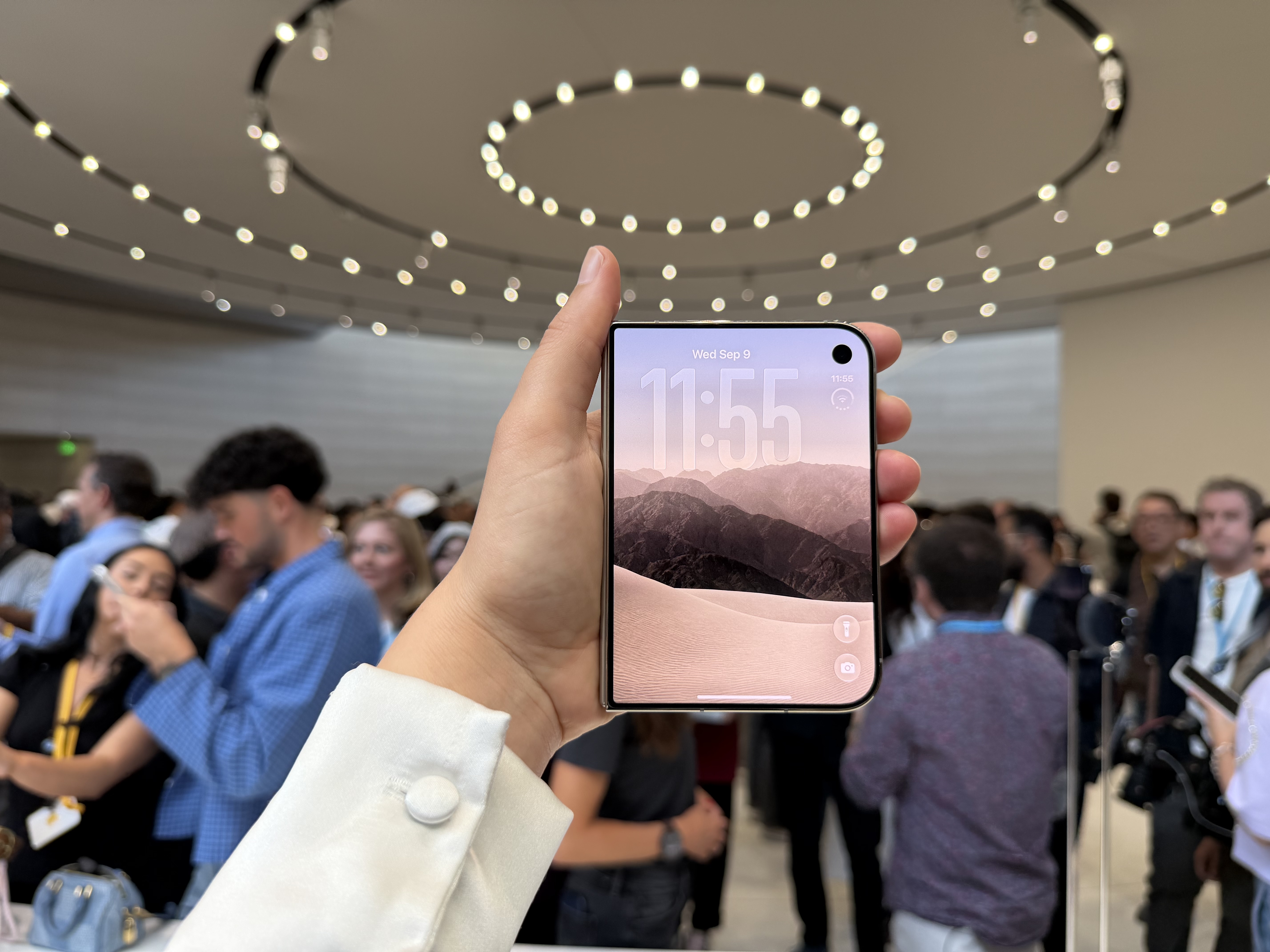 hand holding the iPhone Duo in a busy room, with the front