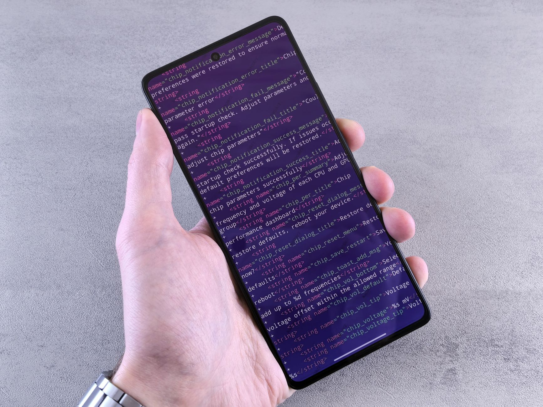 Close-up of a smartphone displaying code text held in a person's hand.