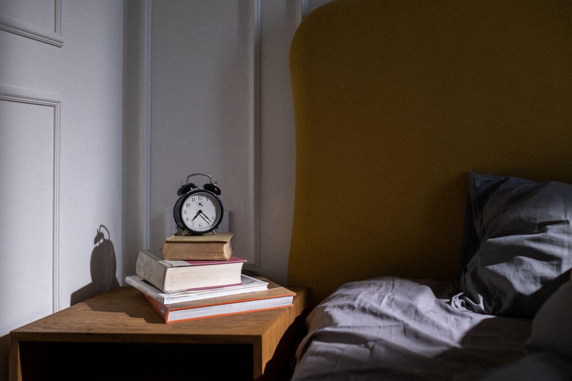 A cozy bedroom setting with books and an alarm clock on a