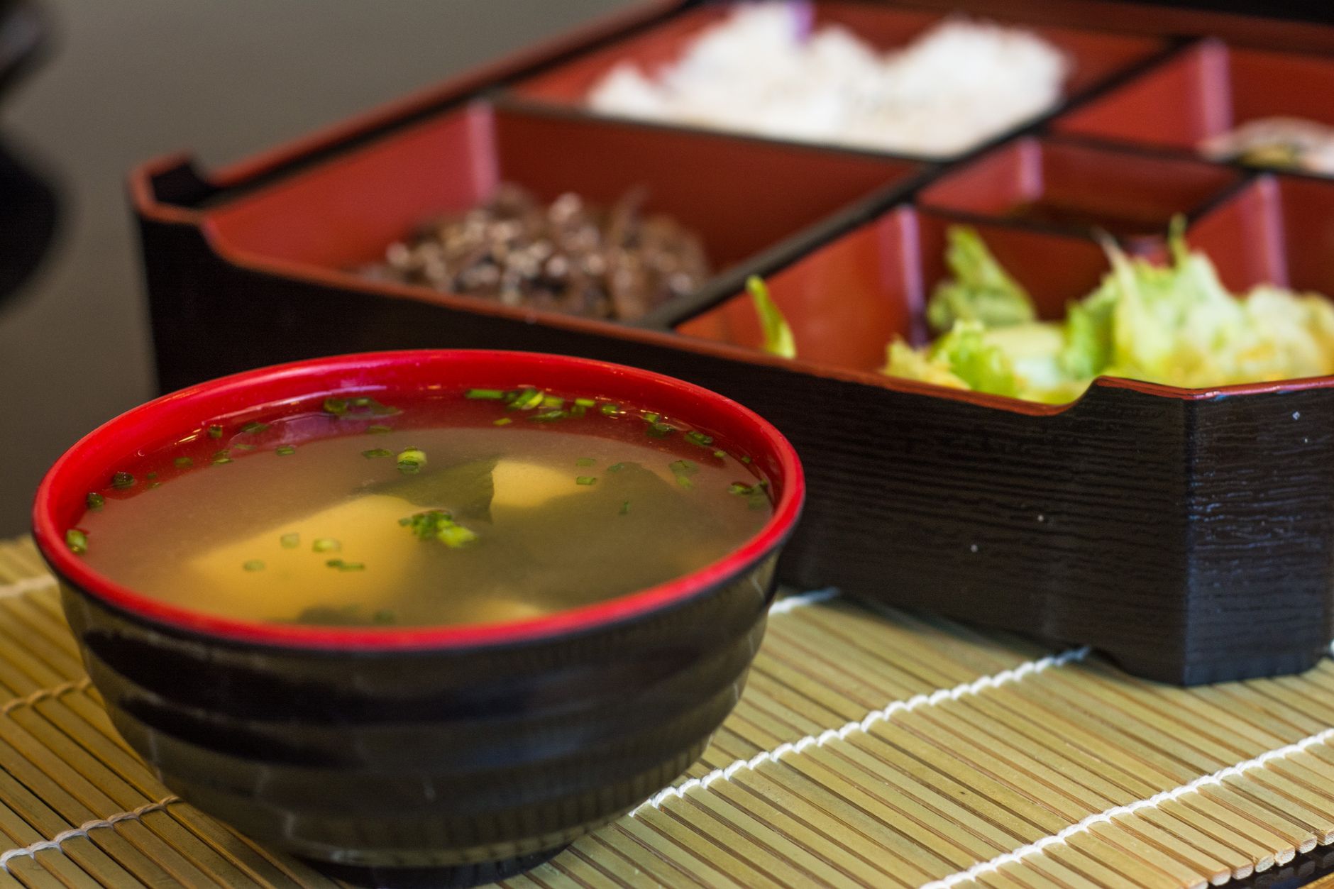 Close-up of a traditional Japanese bento box featuring a bowl of miso