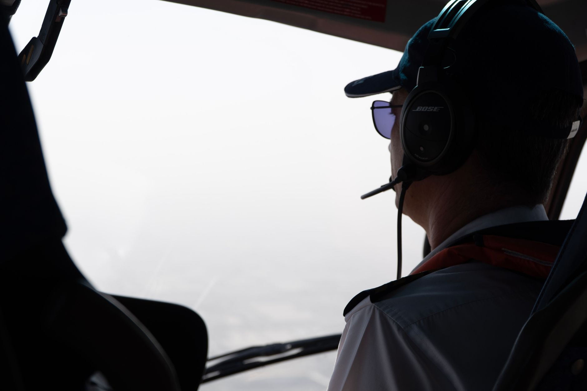 A pilot looks out the cockpit window, wearing a headset during flight.
