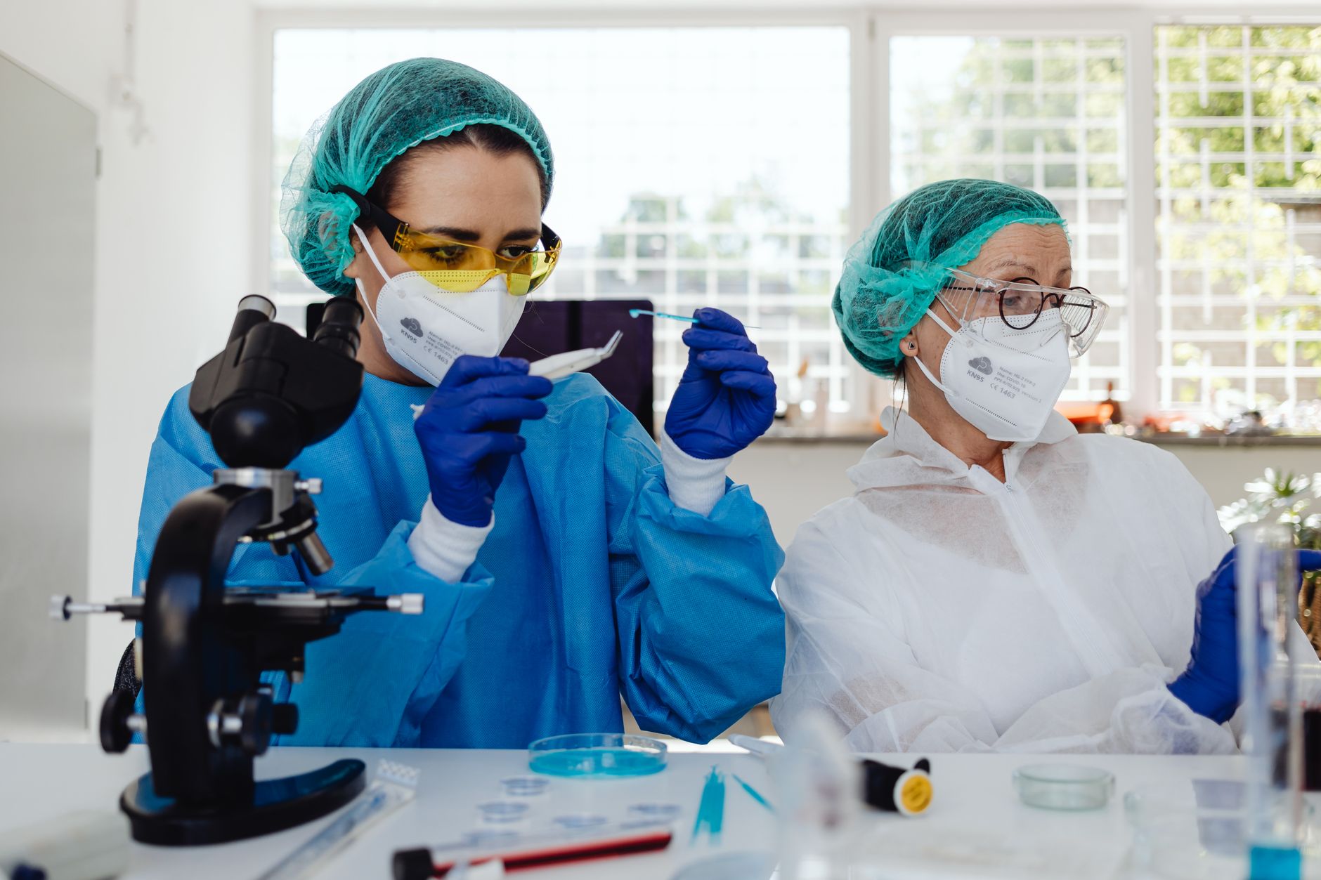Two female scientists wearing PPE working in a lab with a microscope