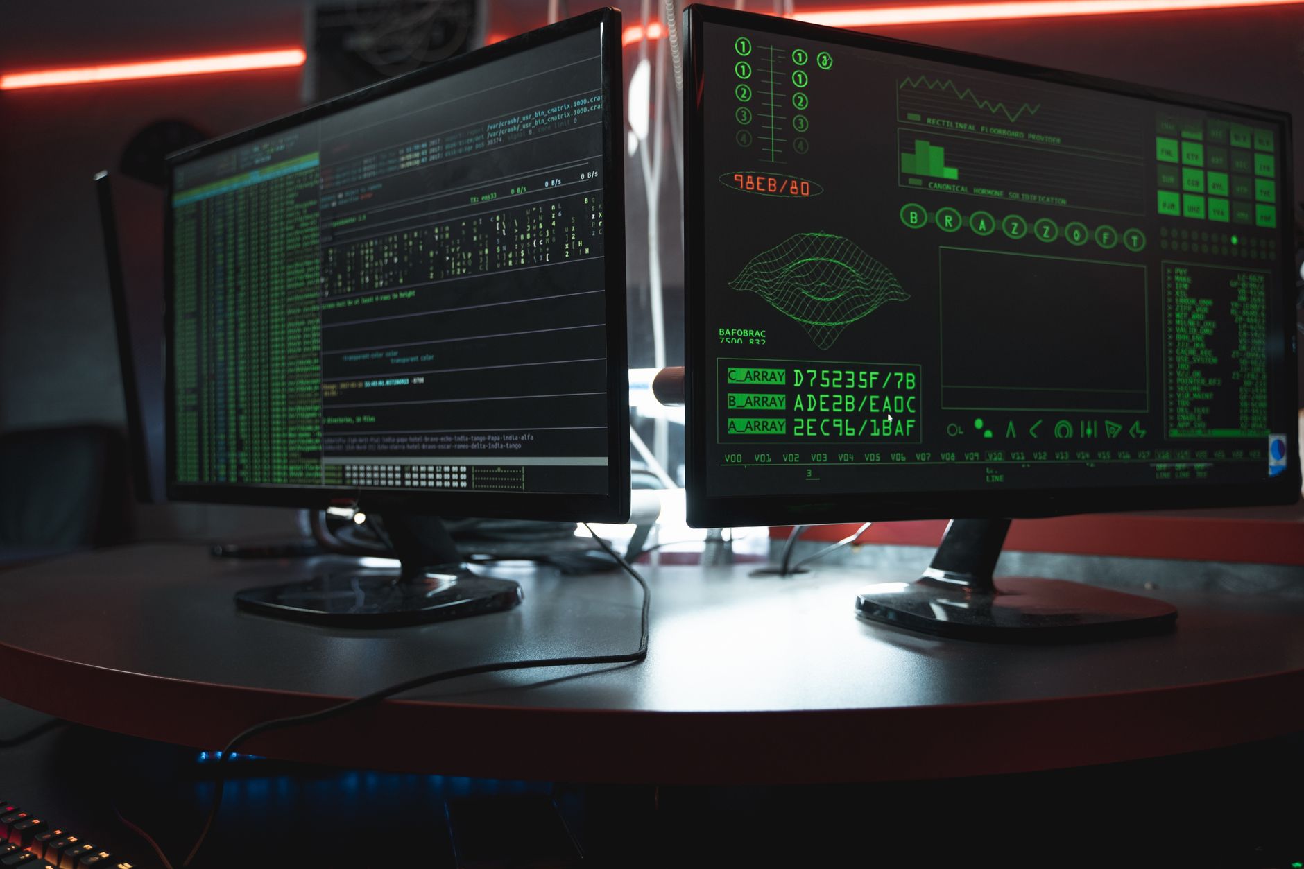 Close-up of dual computer monitors with green coding interfaces in a dark