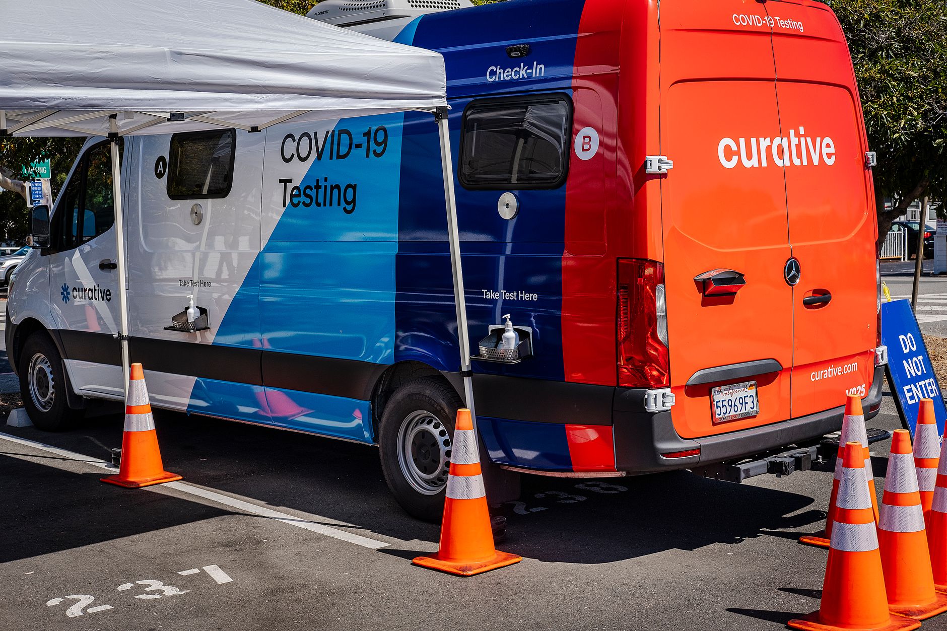 Mobile COVID-19 testing van parked outdoors with safety cones and signage.