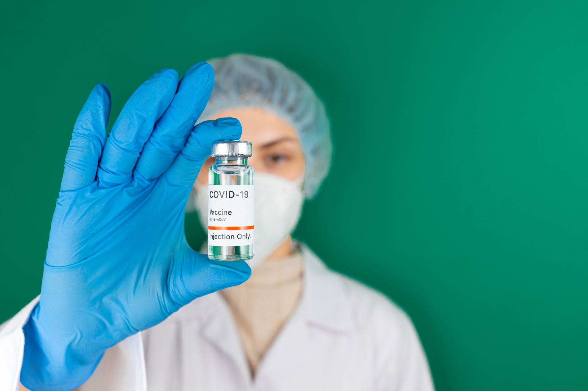 Medical professional holding a COVID-19 vaccine vial in a studio setting with