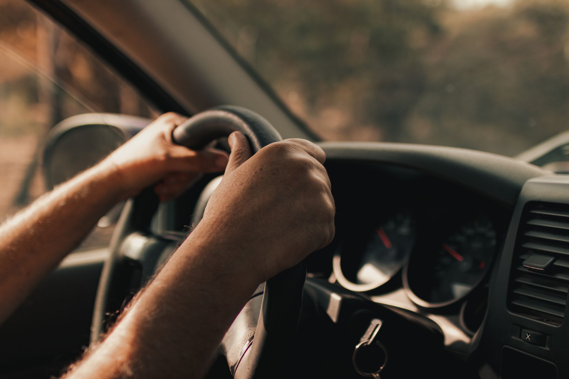 Driver's hands on a steering wheel inside a vehicle, focusing on the