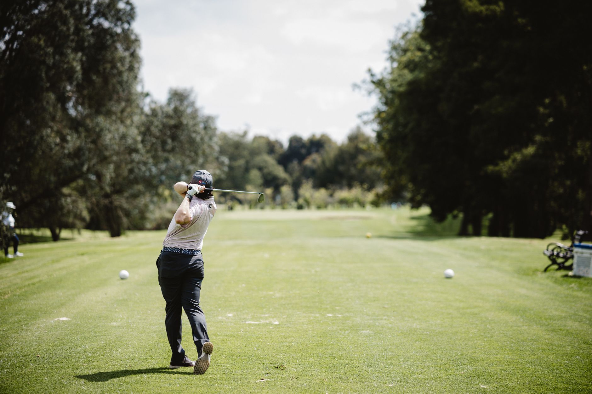 A golfer swings on a bright day in Bogotá, Colombia's lush green