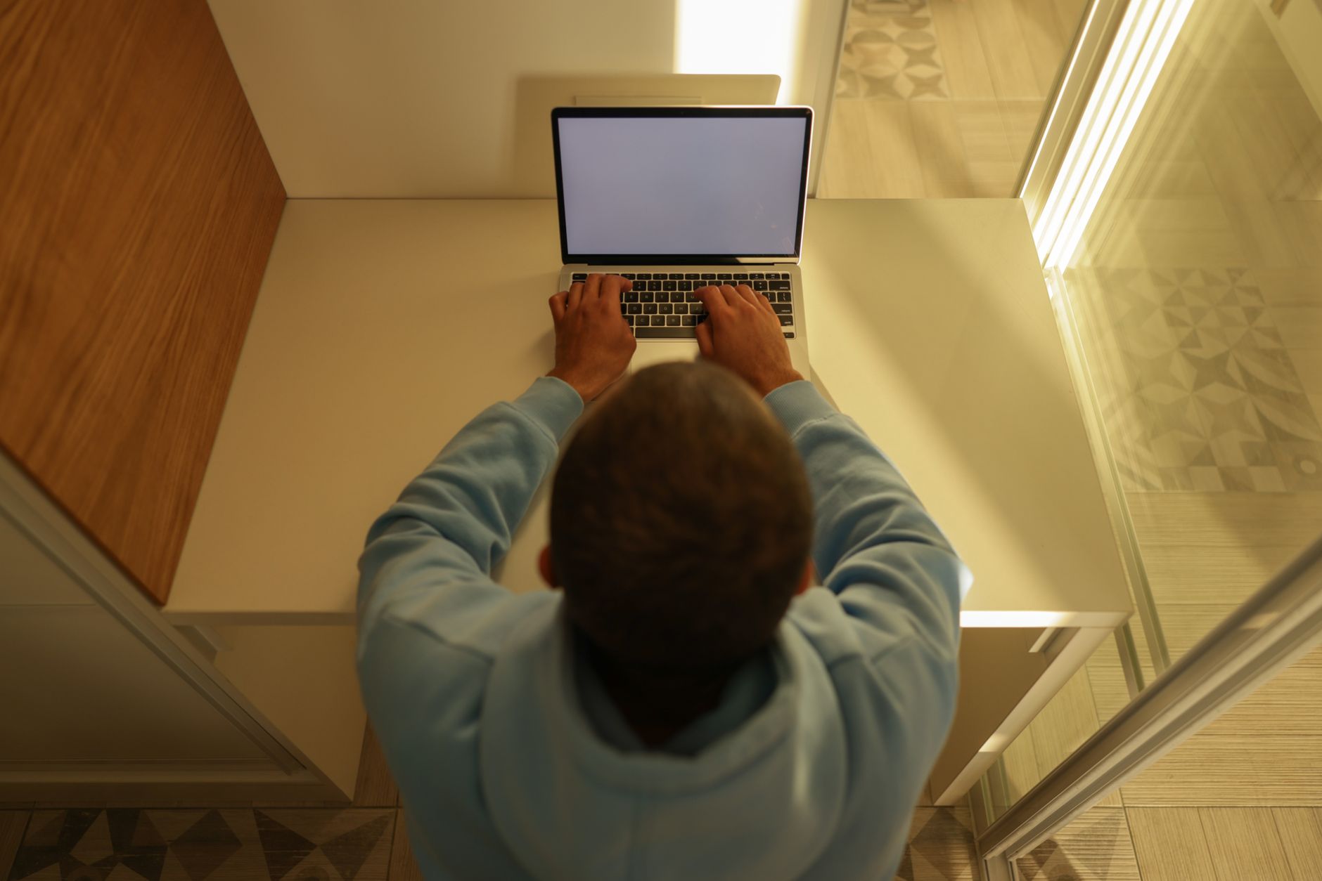 Overhead view of a man typing on a laptop with a blank