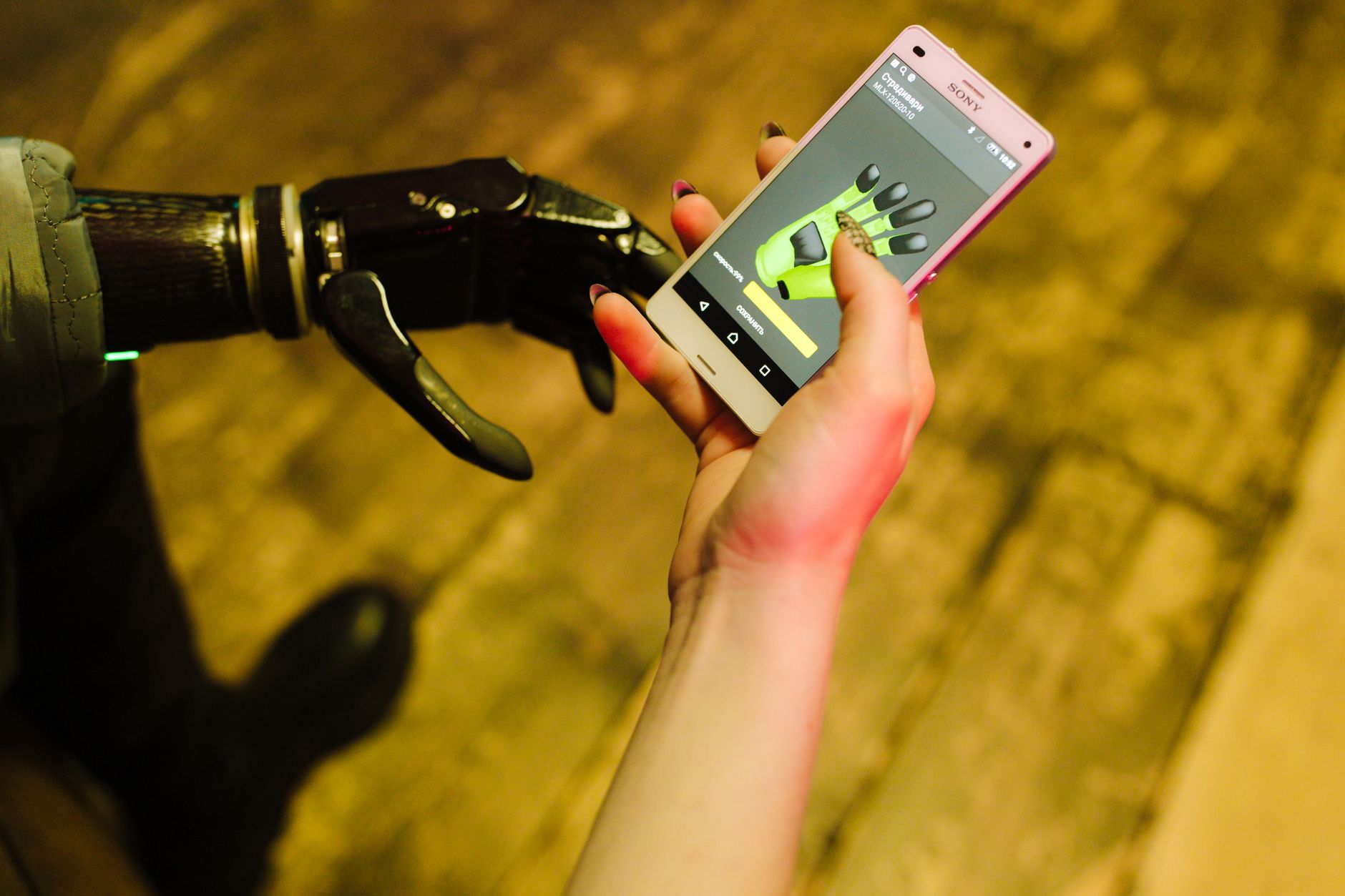 A close-up of a prosthetic hand interacting with a smartphone showcasing futuristic