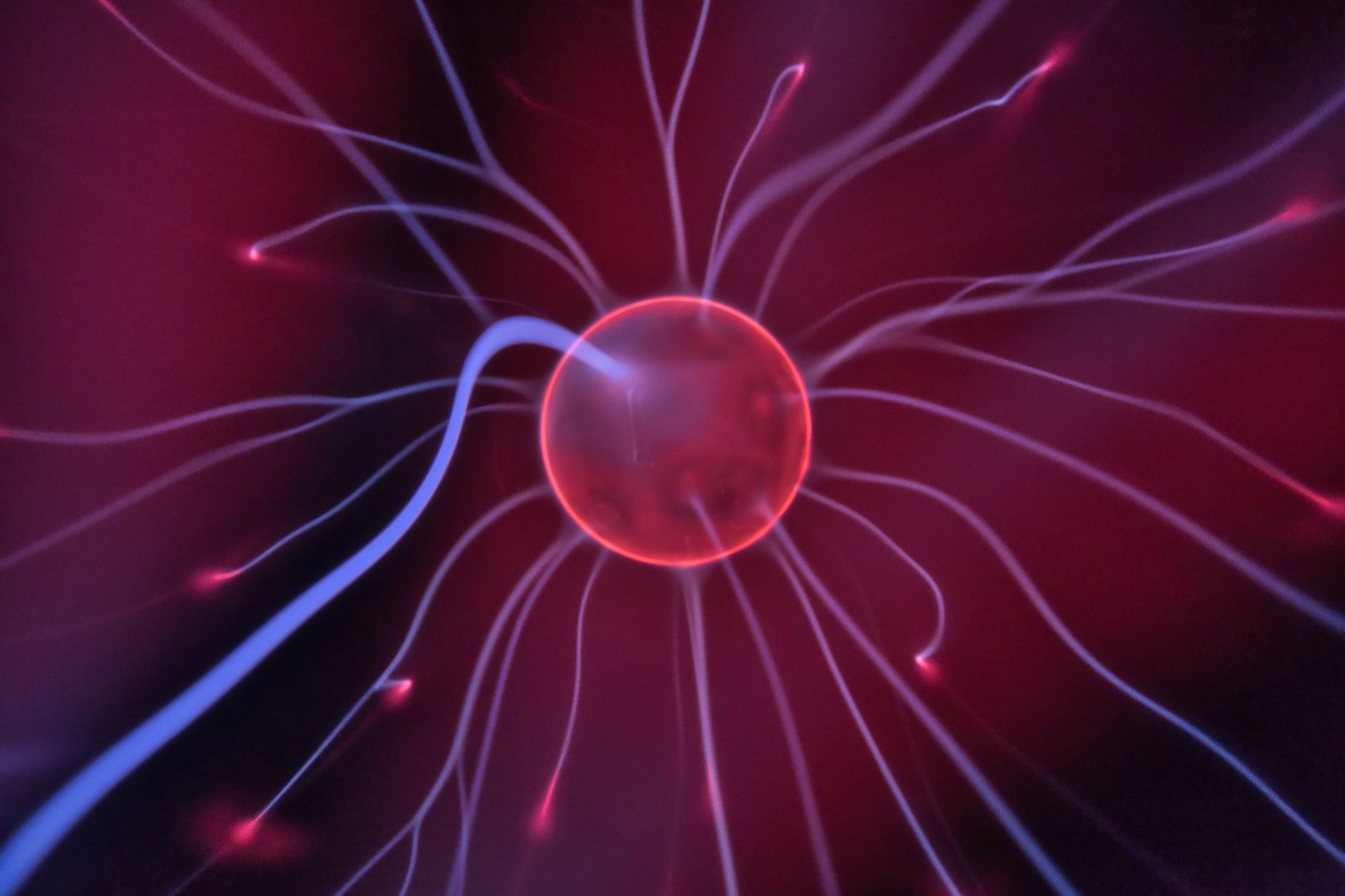 Close-up of a glowing plasma ball with colorful electric currents reaching outwards.