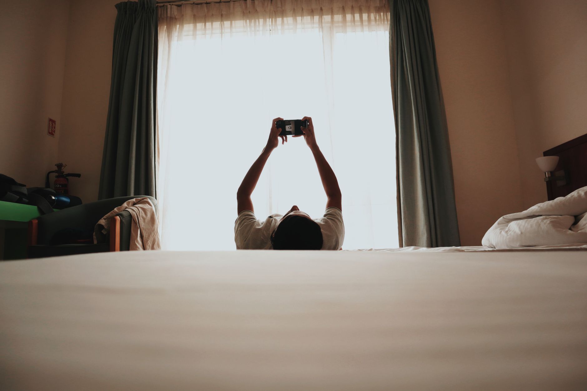 A man lies in bed using a smartphone, creating a relaxed and