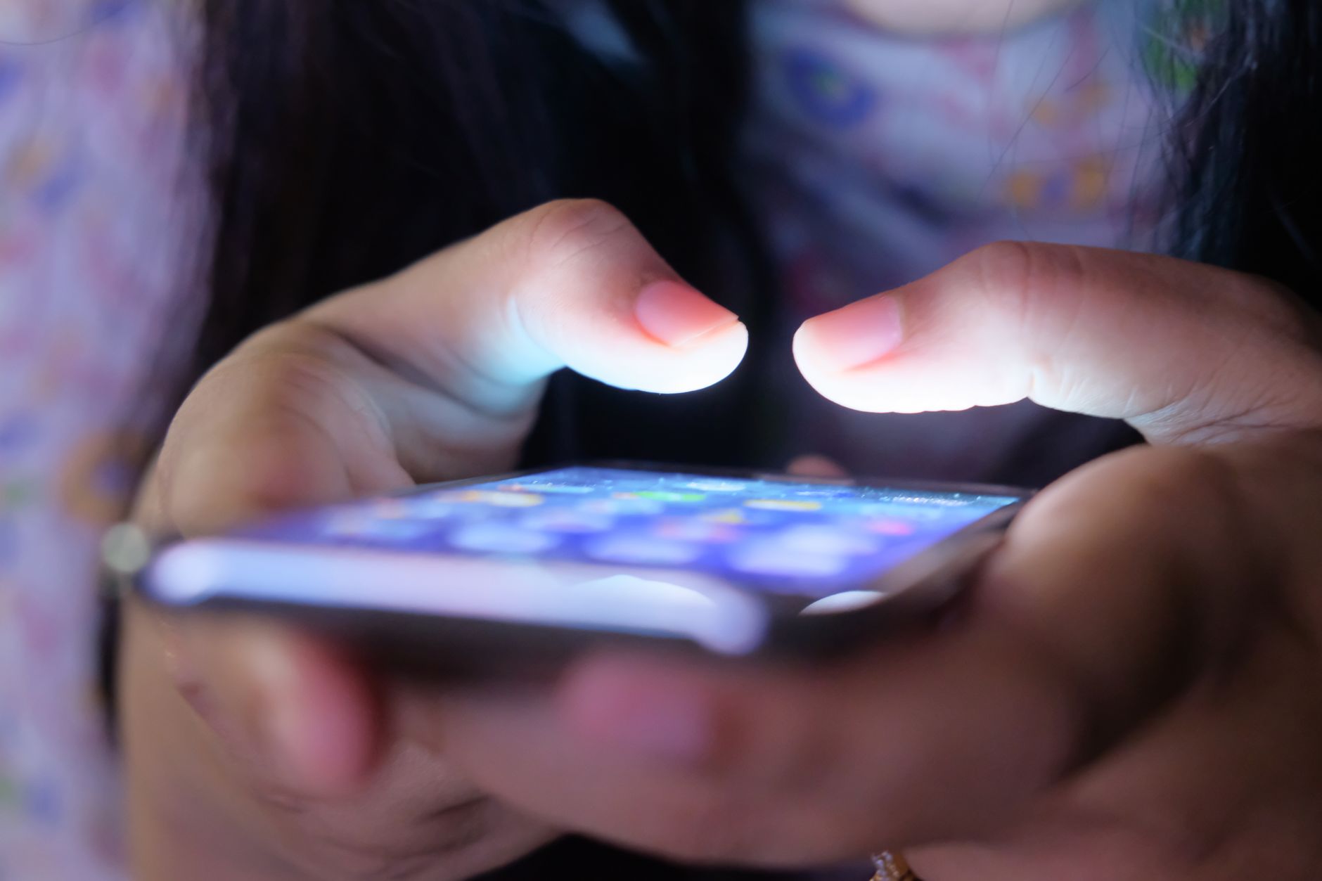 A close-up shot of hands holding a smartphone in low light, showcasing