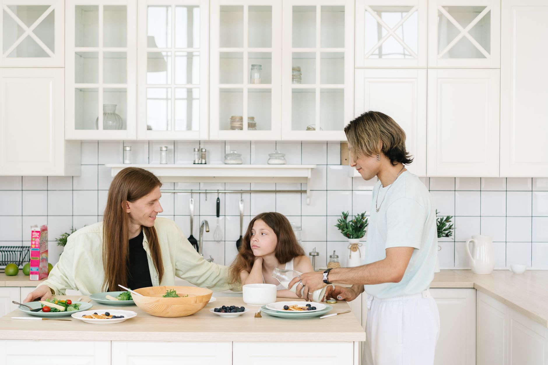 A family enjoys breakfast together in a bright, modern kitchen setting.
