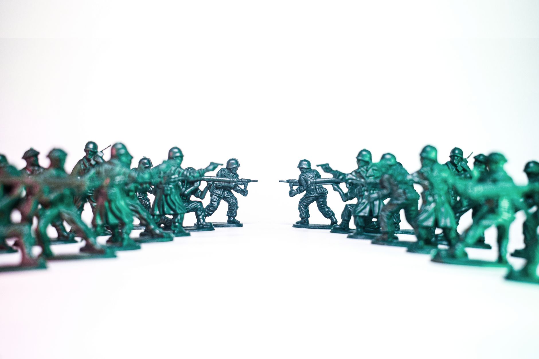 Green toy soldiers facing off on a white background, symbolic of conflict