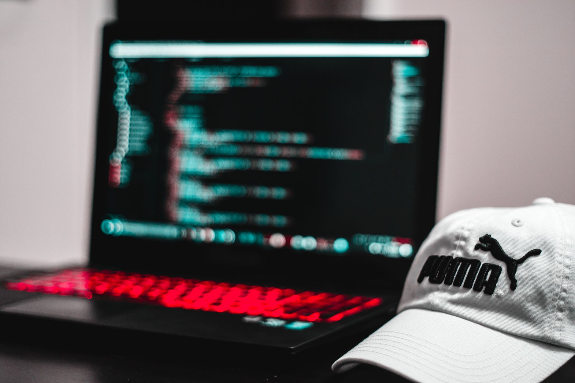Blurred laptop screen displaying code with a white cap in focus, depicting