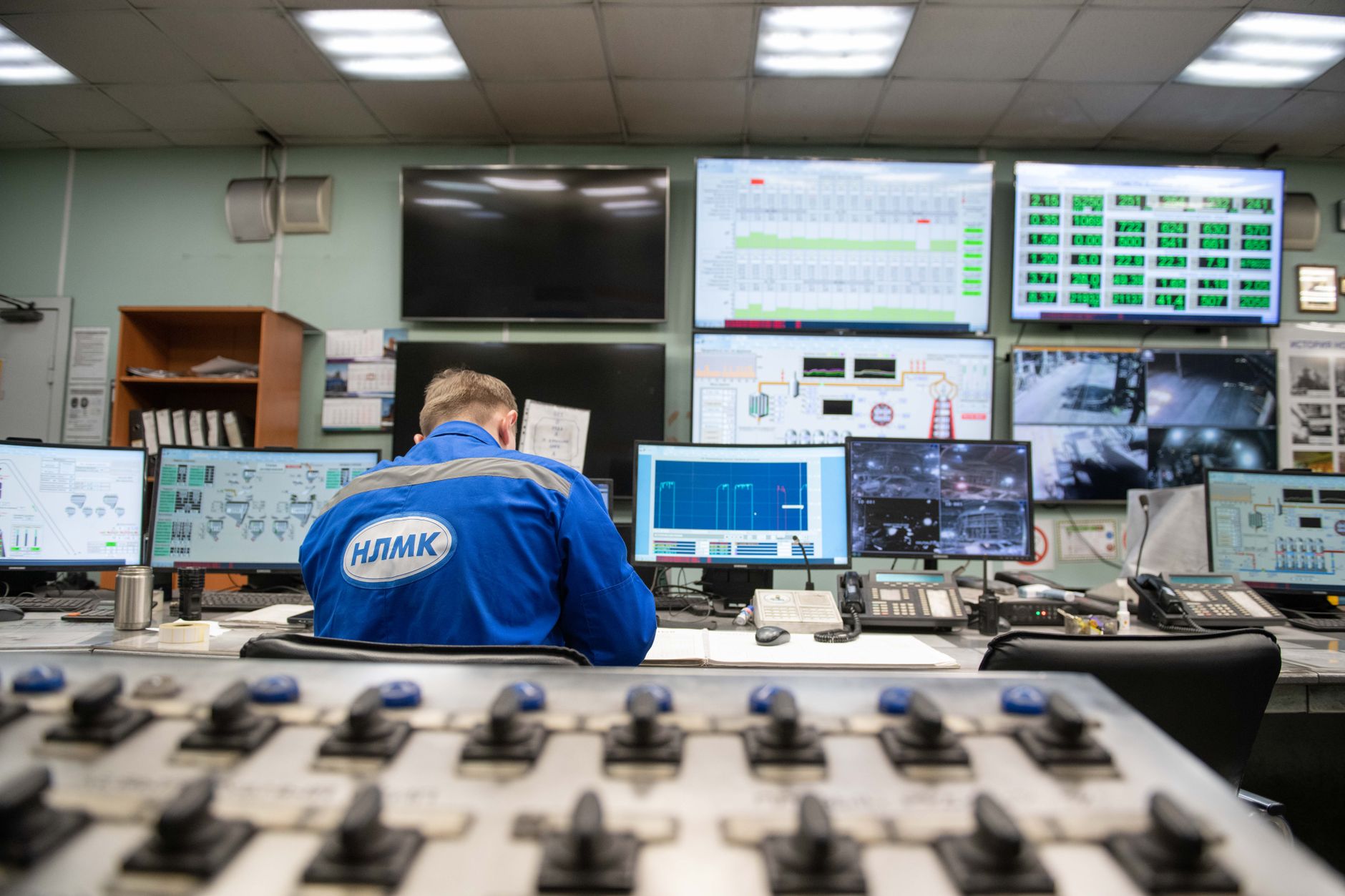 An engineer monitors multiple screens in an industrial control room, ensuring smooth