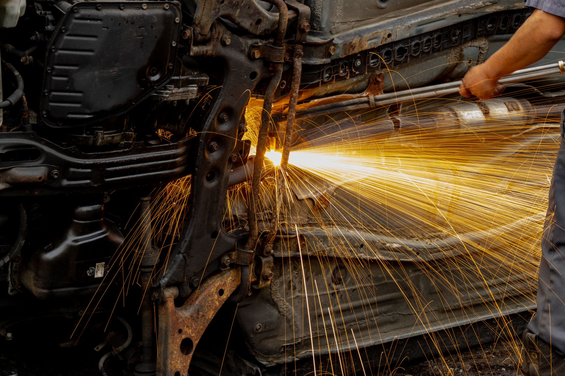 Mechanic welding car engine parts, with bright sparks flying. Hands-on automotive repair