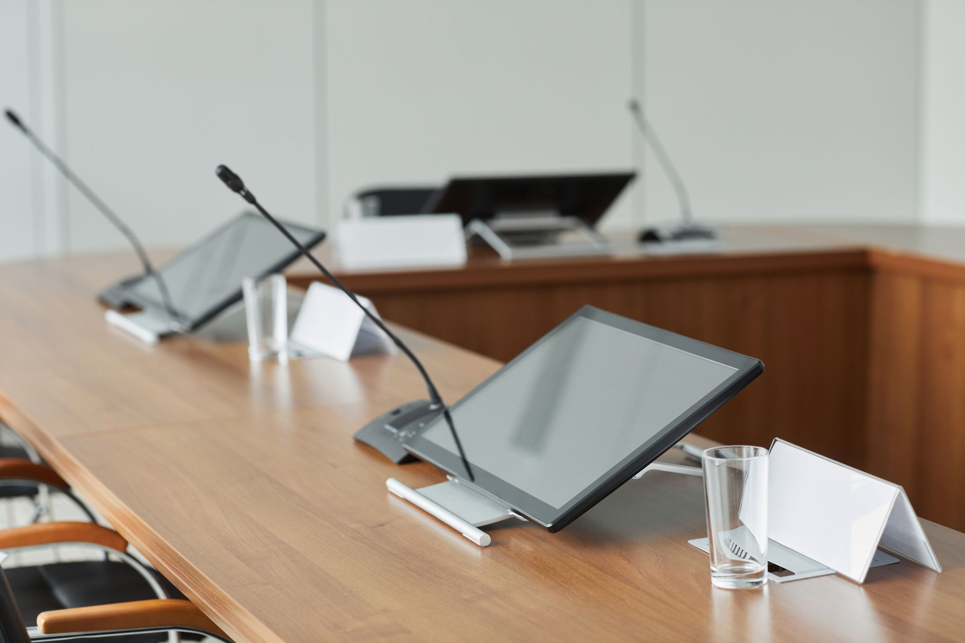 A modern conference room featuring sleek monitors and microphones on a wooden