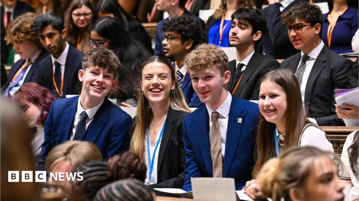 Members of Youth Parliament smile while sat on the benches of the