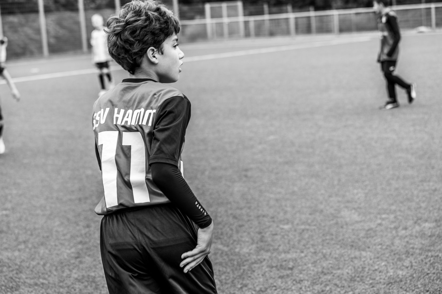 A young soccer player on a football pitch wearing a team jersey