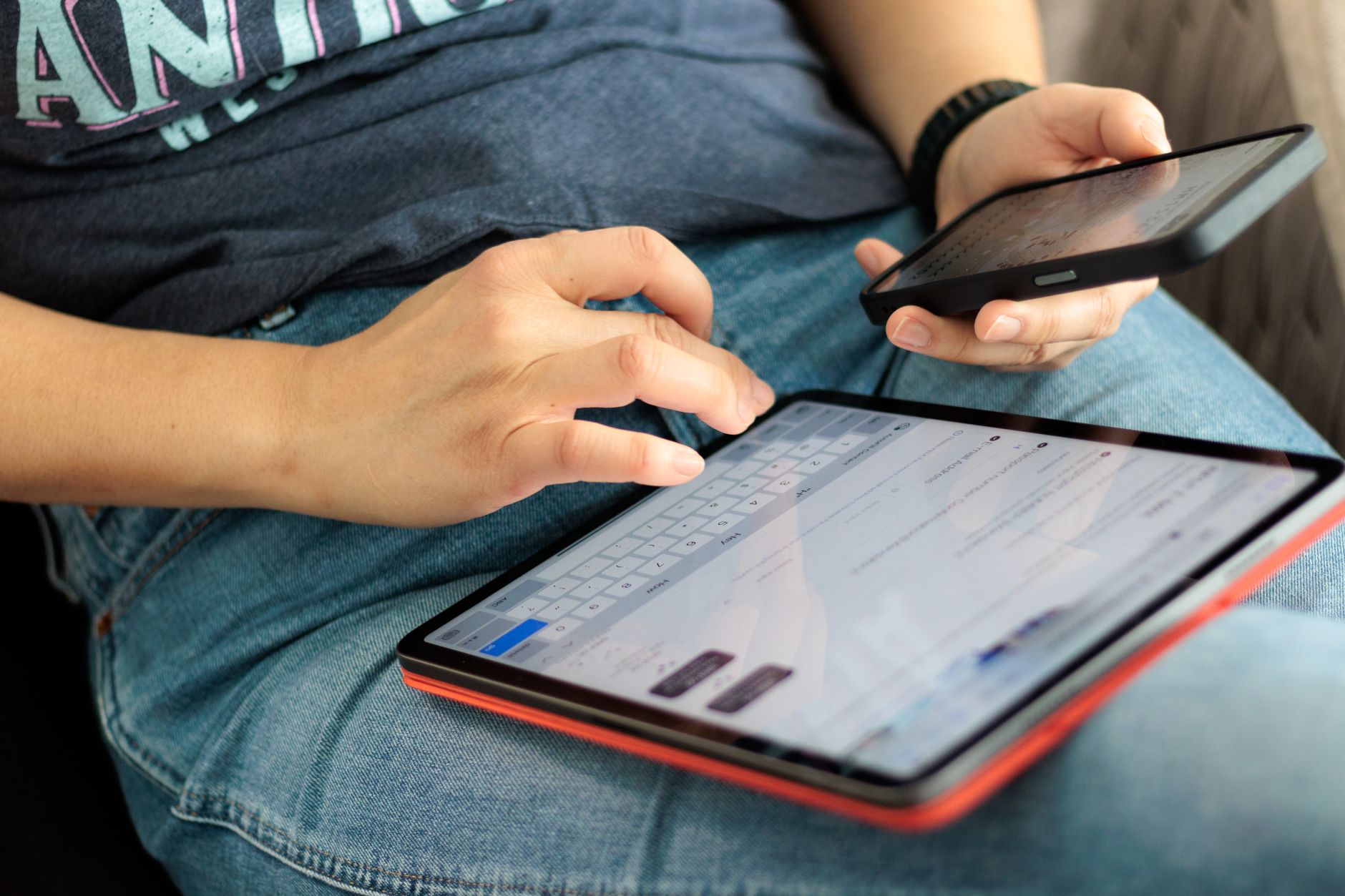Close-up of adult using a tablet and smartphone indoors, showcasing digital connectivity