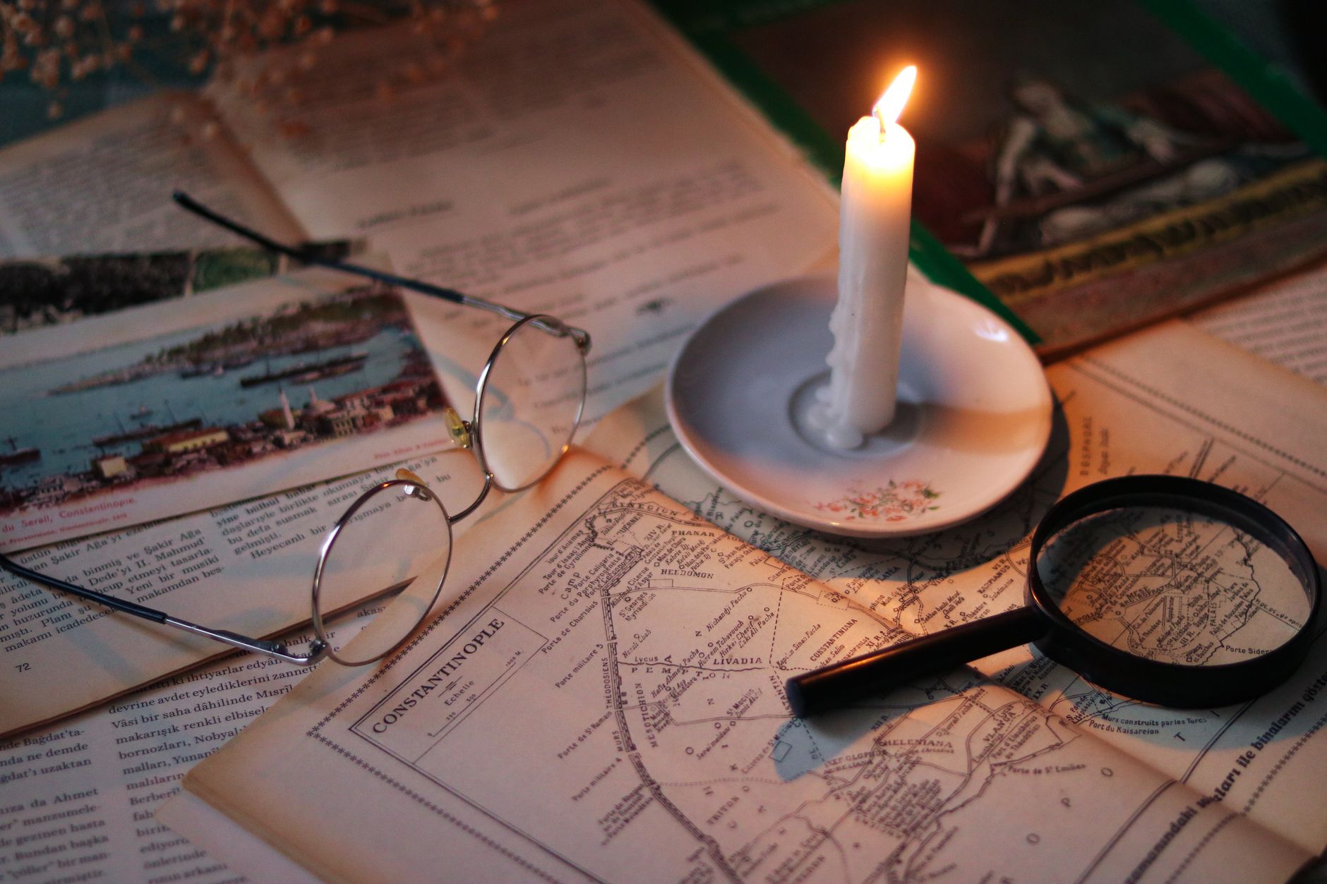Cozy vintage scene with candle, map, glasses, and magnifying glass.