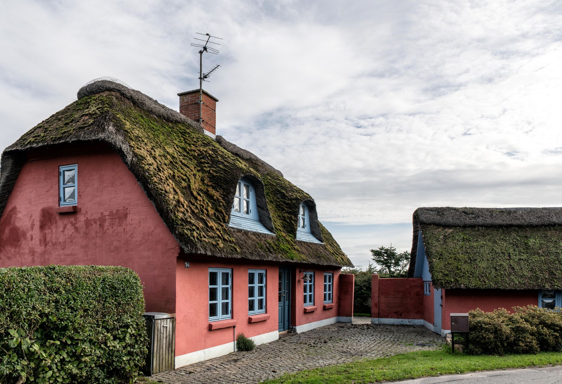 Charming thatched cottages with red walls in Haderslev, Denmark under a cloudy