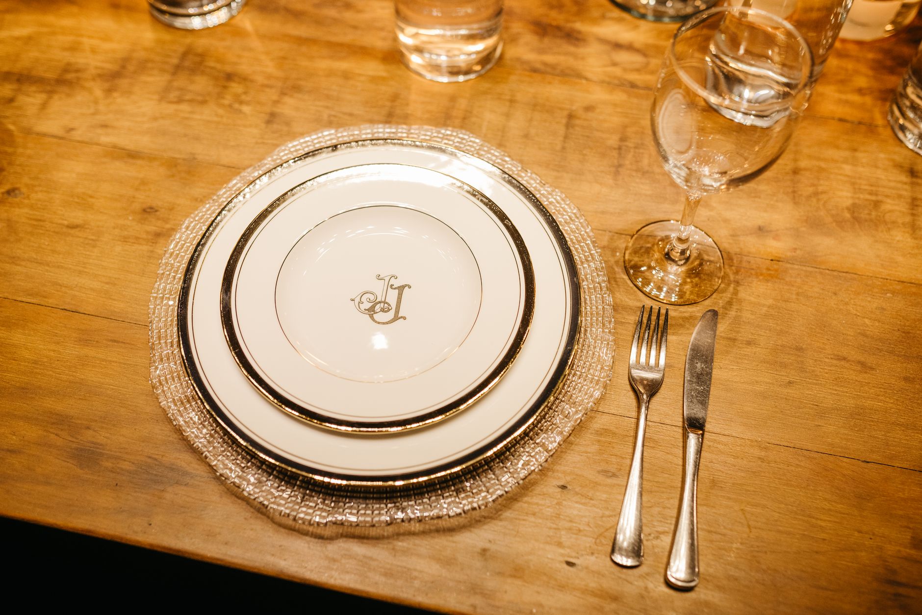 Luxurious dinner setting with monogrammed plates, cutlery, and glassware on a wooden