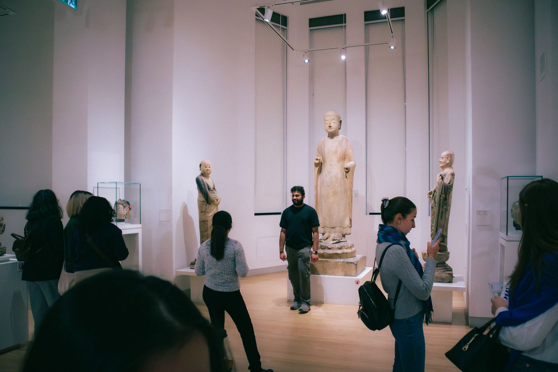 People exploring a Toronto art museum showcasing historic Buddha statues from Chinese